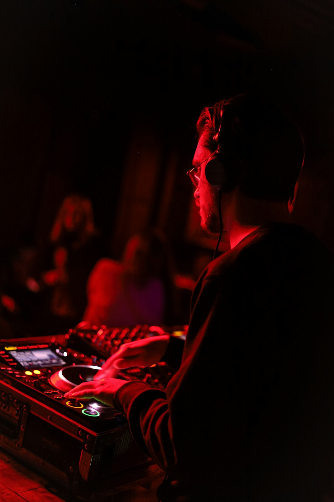 Sound engineer adjusting a mixing console with waveform monitors in a broadcast studio
